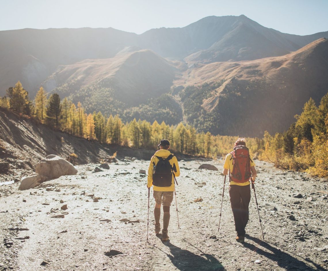 Dos viajeros de espaldas caminando hacia un valle de montaña